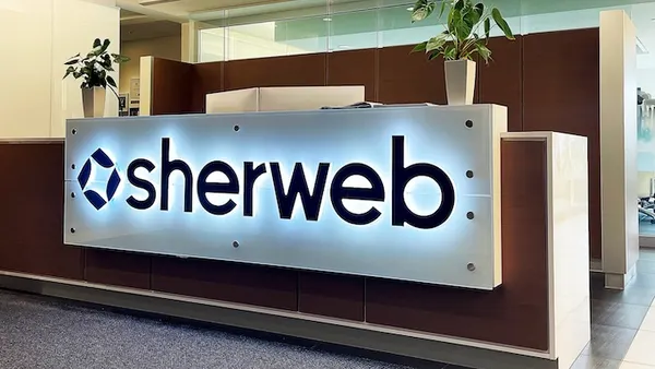 An office lobby with the Sherweb corporate logo visible on the front of the reception desk.