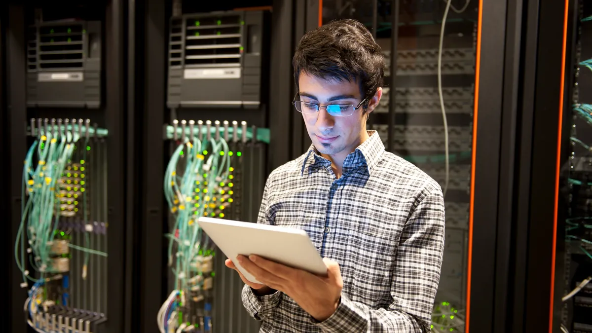 An IT technician programming computer equipment in a server room.