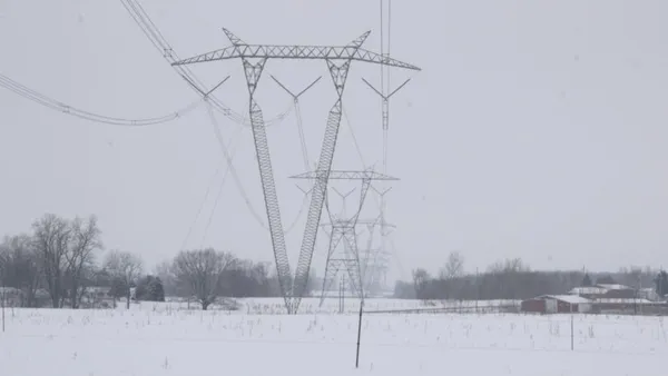 High-voltage electric power lines run across a snowy field.