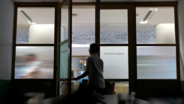 A worker leaves a darkened boardroom after a meeting