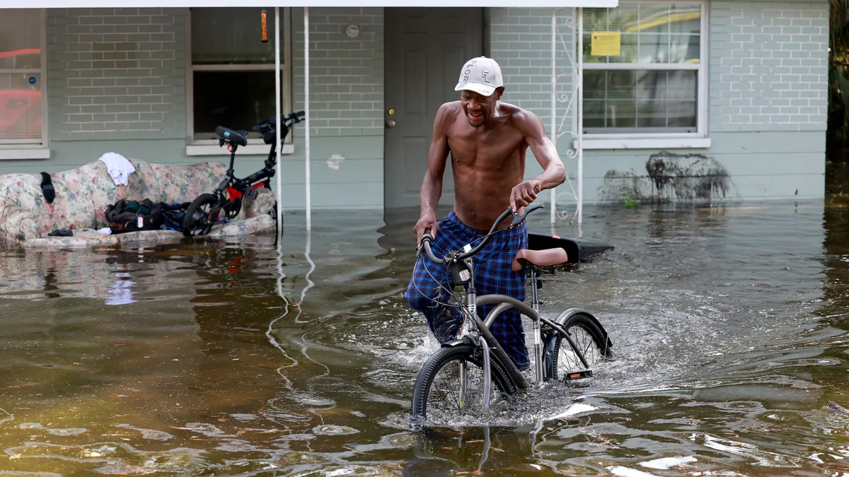 A man walks his bike through flood waters.