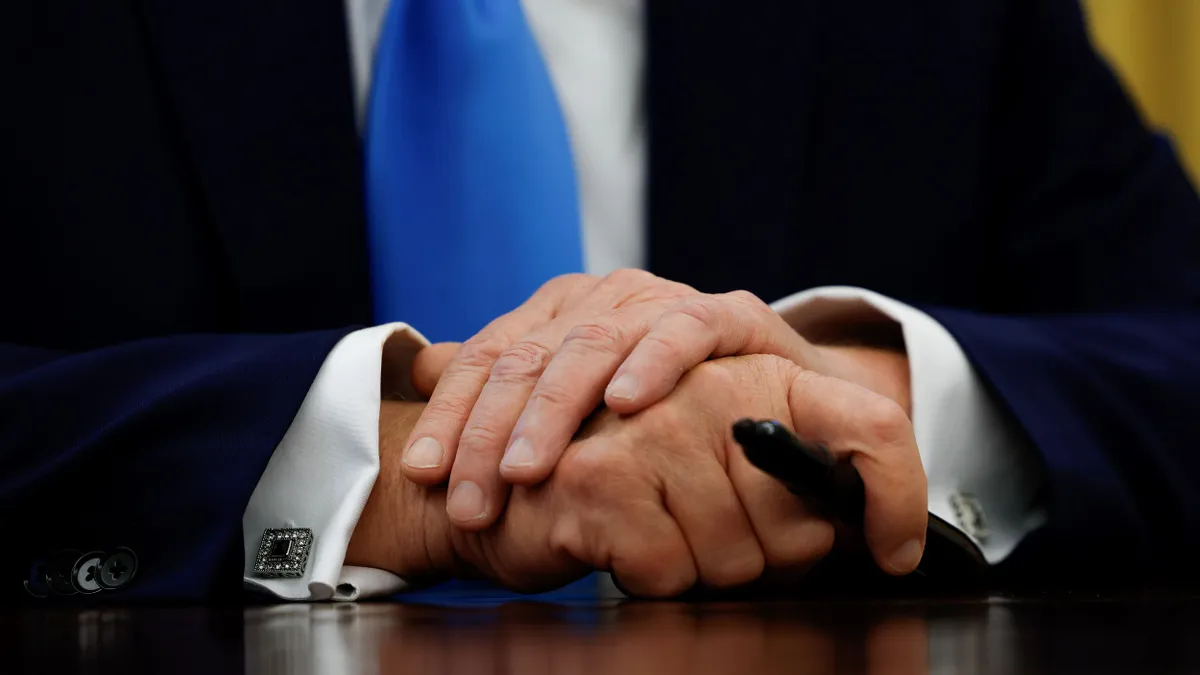 A detail view of President Donald Trumps hands as he holds a pen.