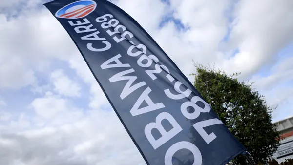 A flag reading "Obamacare" and with the exchanges' logo waves in front of an insurance agency.