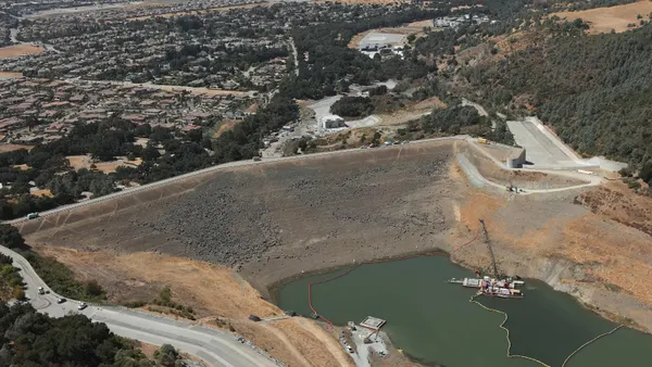 An aerial shot of an earthen embankment dam, a large mount that separates different elevations of water.