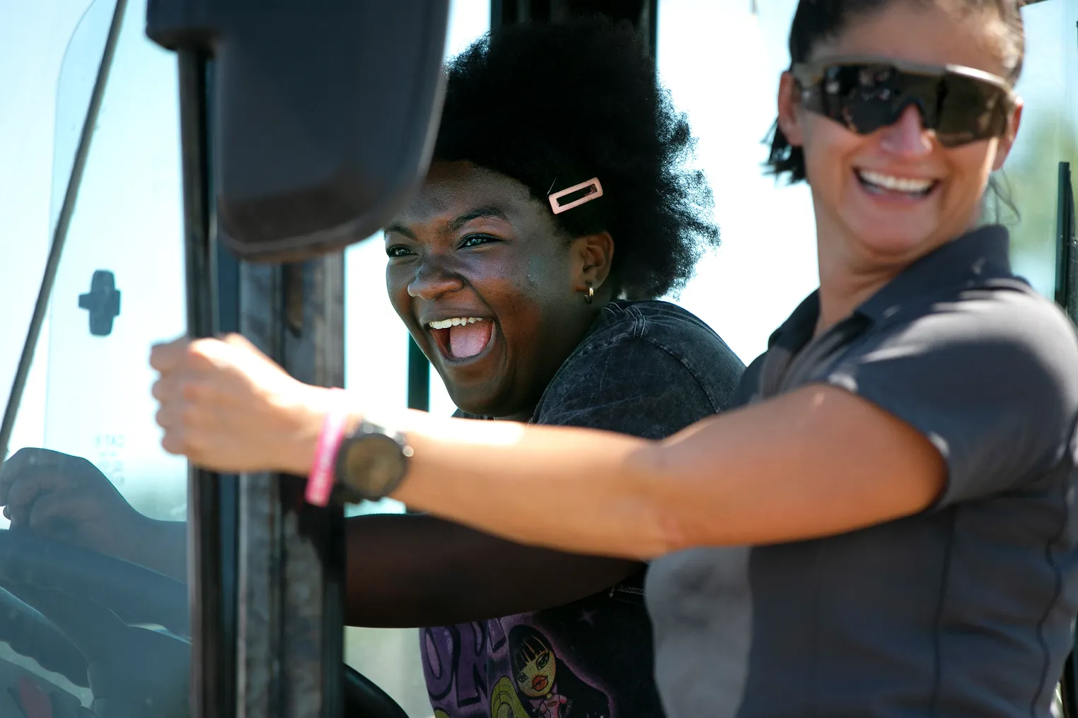 Two women in the cab of a heavy construction machine.