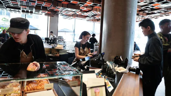 Workers prepare orders behind the counter at a coffee shop.