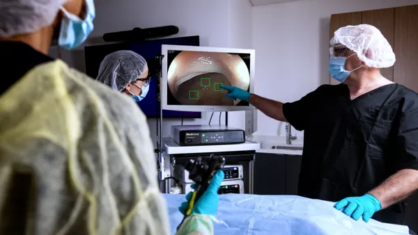 Doctors in surgical attire observe an endoscopic procedure