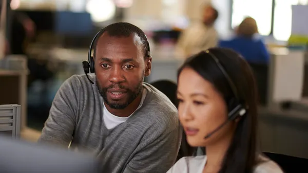 An employee aids his colleague in a call center.