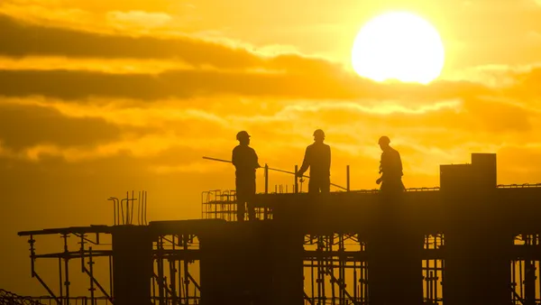 construction workers toil with the sunset in the background