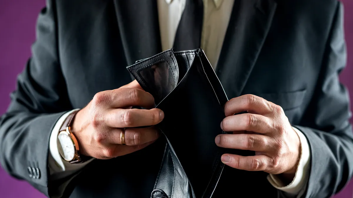a photo of a man in a suit showing an empty black wallet