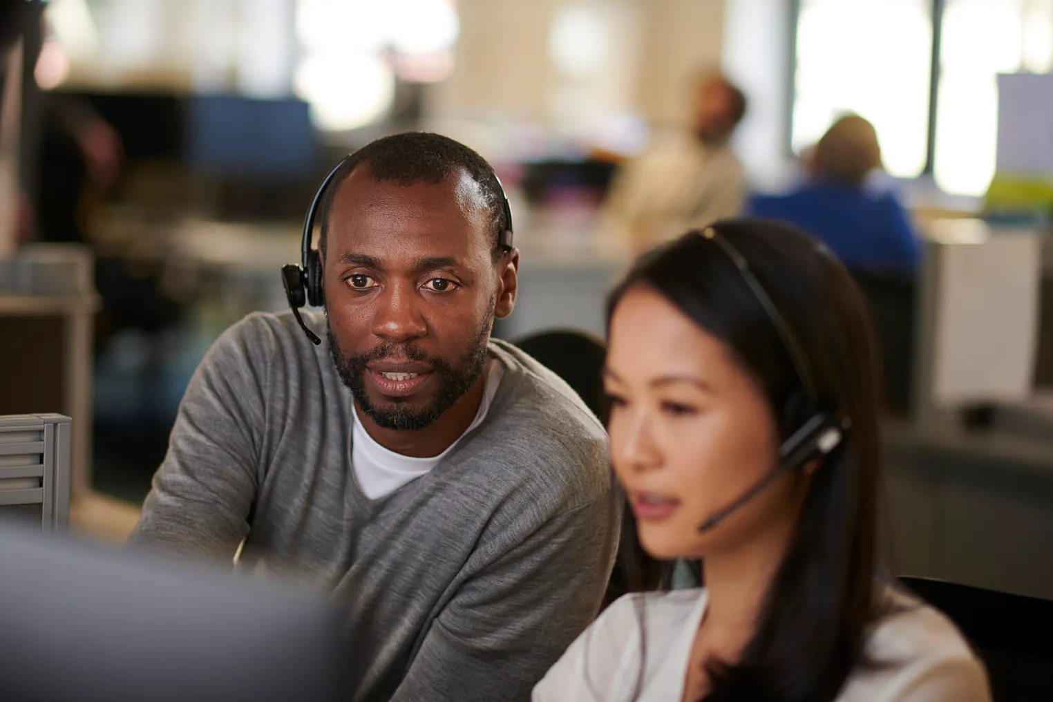 An employee aids his colleague in a call center.