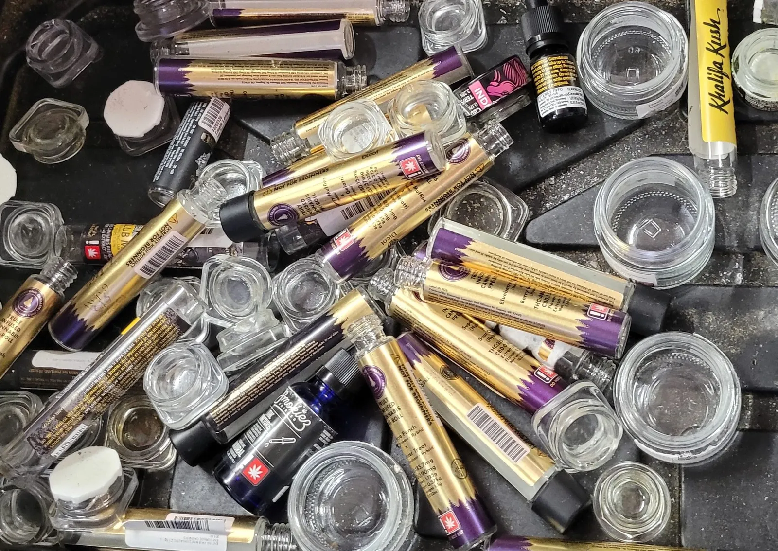A bin with glass tubes and jars with cannabis branding on the outside.