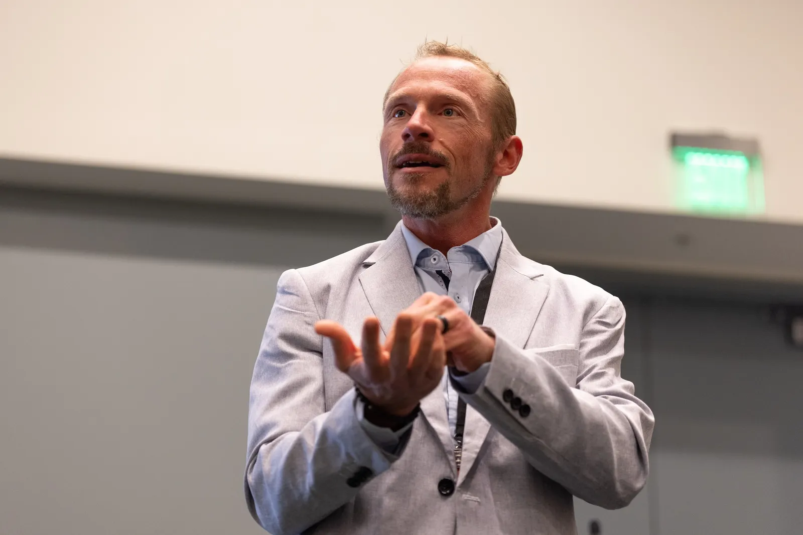 A person is seen speaking in a room. Their upper body is shown