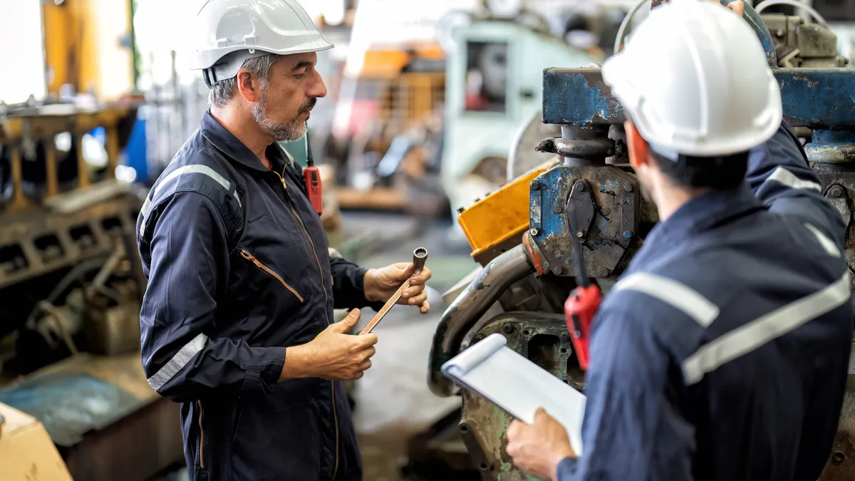 Two maintenance workers inspect a machine.