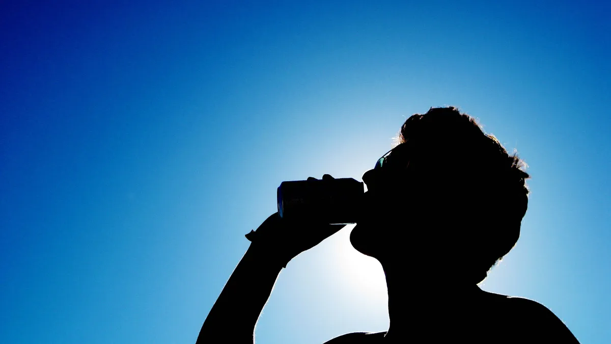 A man drinking from a can in the heat of the sun