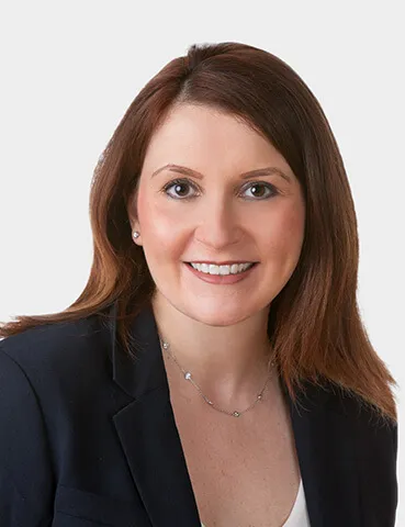 A woman with long reddish brown hair and a dark suit.