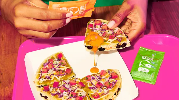 A close up image of a person holding up a slice of Mexican Pizza from Taco Bell