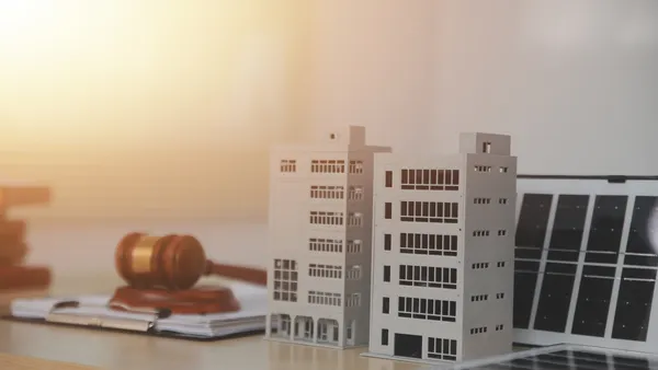 Stock image of a gavel and model apartment building.