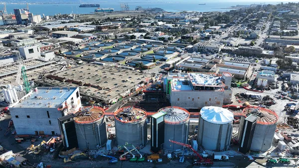 A broad, overhead shot of a water treatment facility, with thick silos and pools of water.