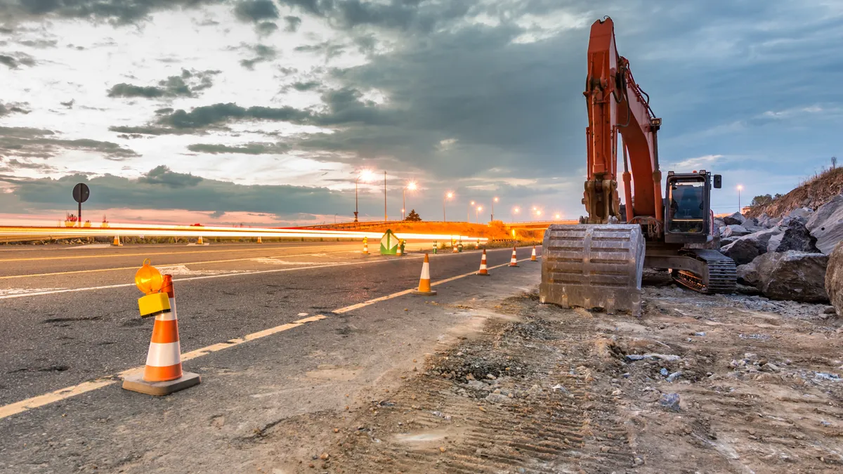 A roadway construction site is backlit by the sun.