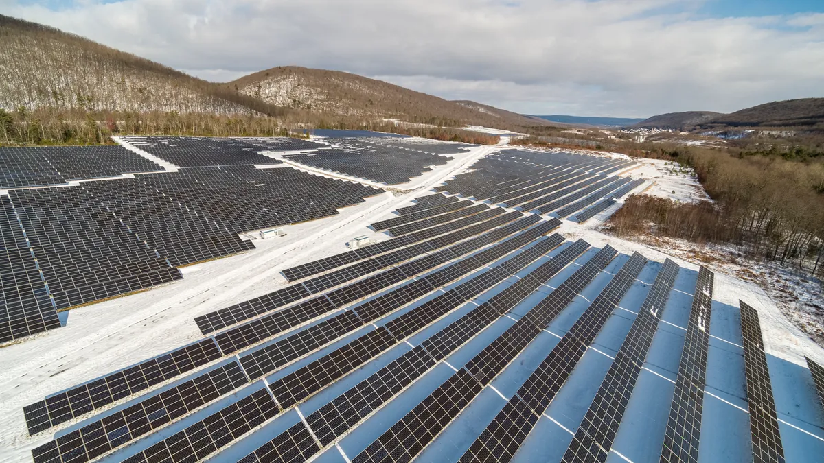 Big solar farm in the Appalachian Mountains, Pennsylvania, on a sunny winter day after a snowfall.