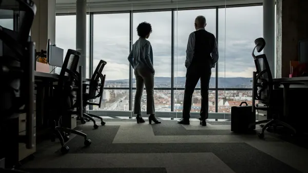Rear view of business colleagues looking through window from the office