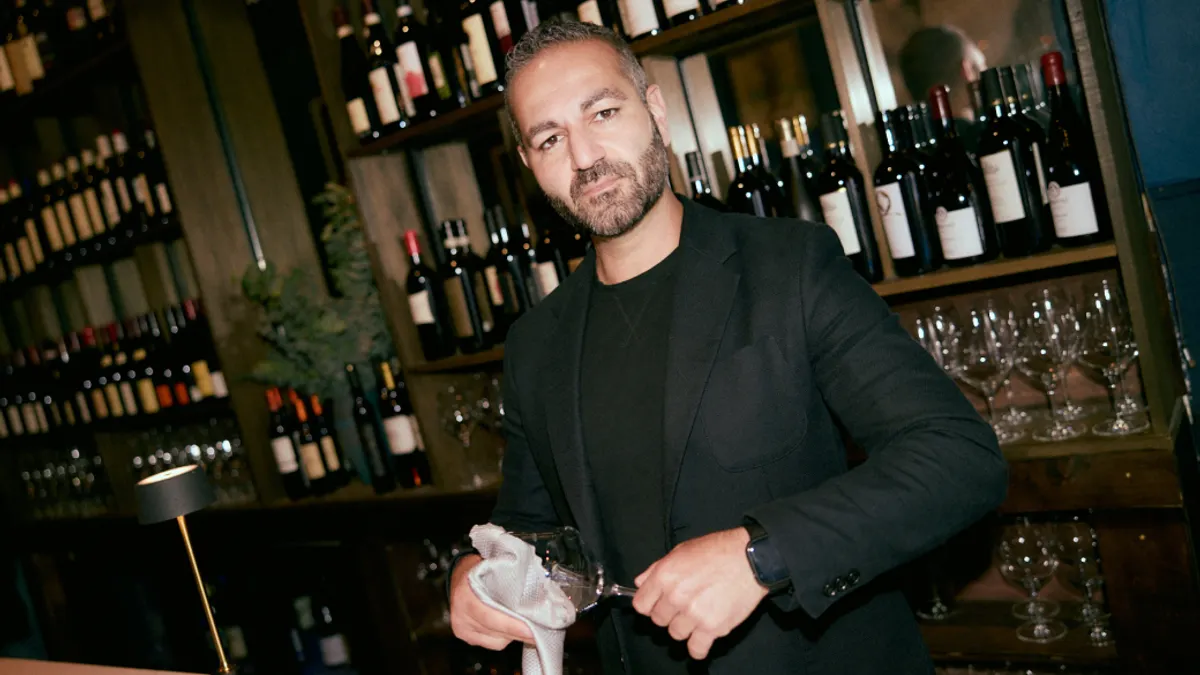 A worker in a fine restaurant cleaning a wine glass.