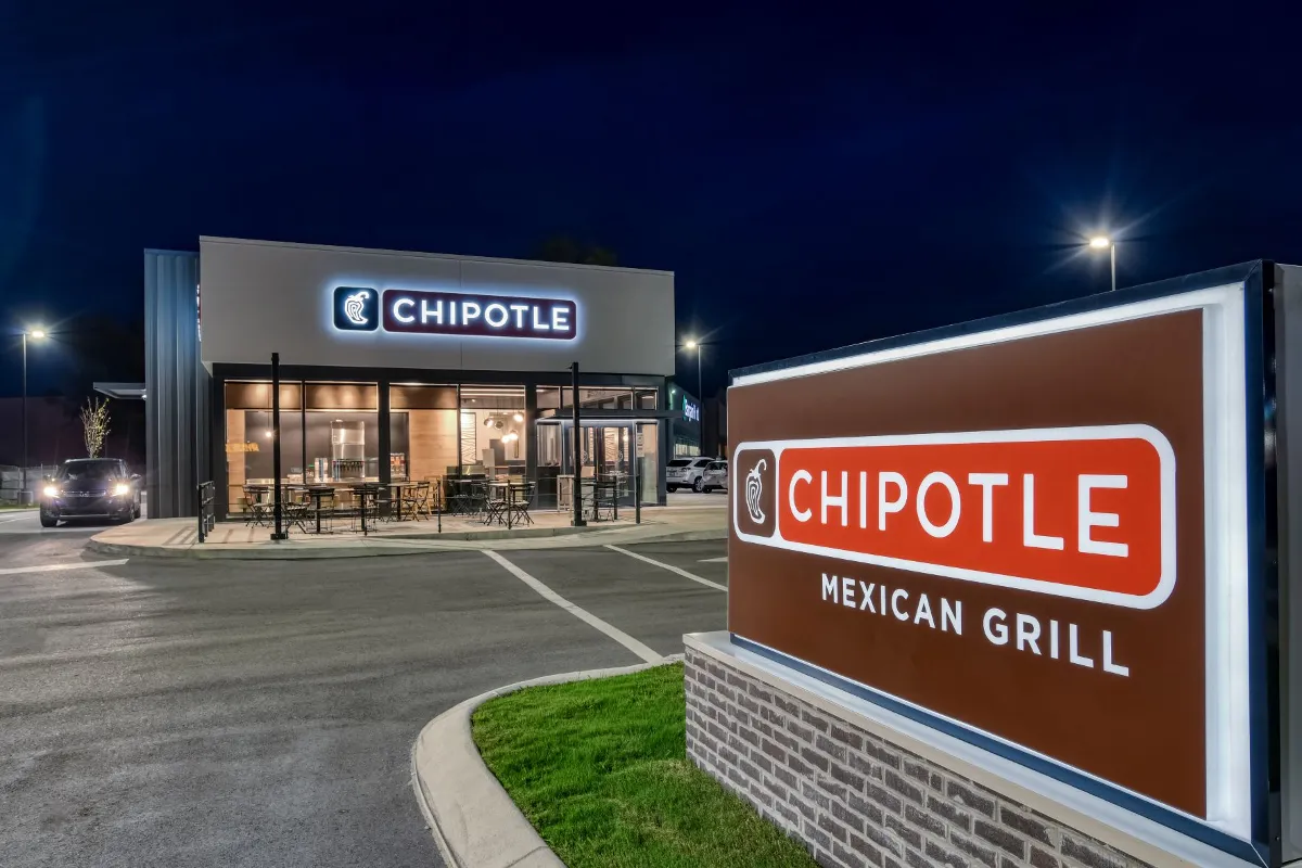 An image of a a white building with Chipotle signage at night.