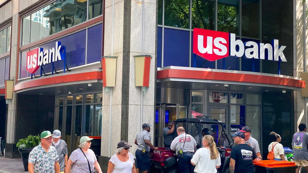 A corner location of a stone-and-glass building with "U.S. Bank" signage is shown as people pass by on the street.