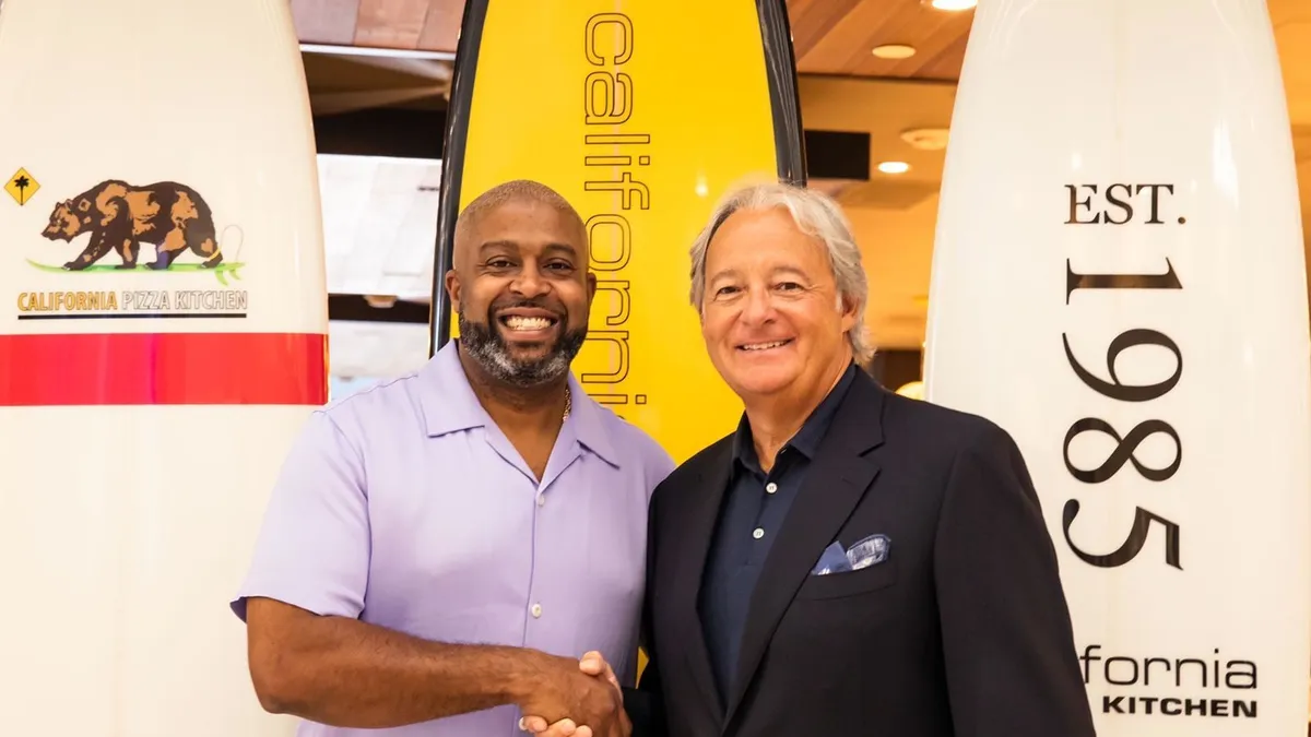 An image of two men standing in front of surfboards.