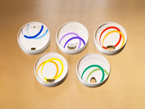 Five multicolored, fiber cup lids arranged next to each other.