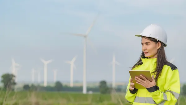 Engineer working and holding a report at a wind turbine farm.