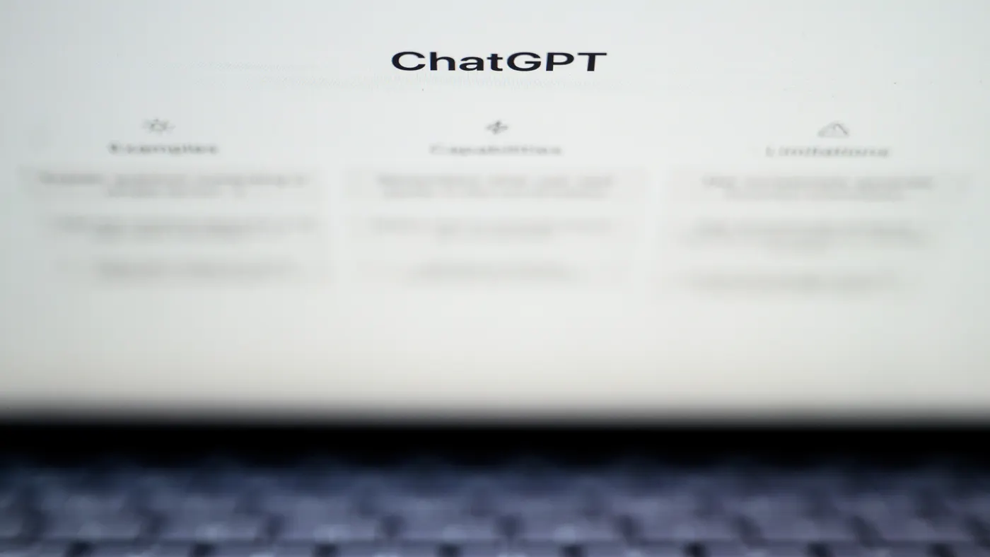A laptop screen shows the word "ChatGPT" and three columns of blurred-out text