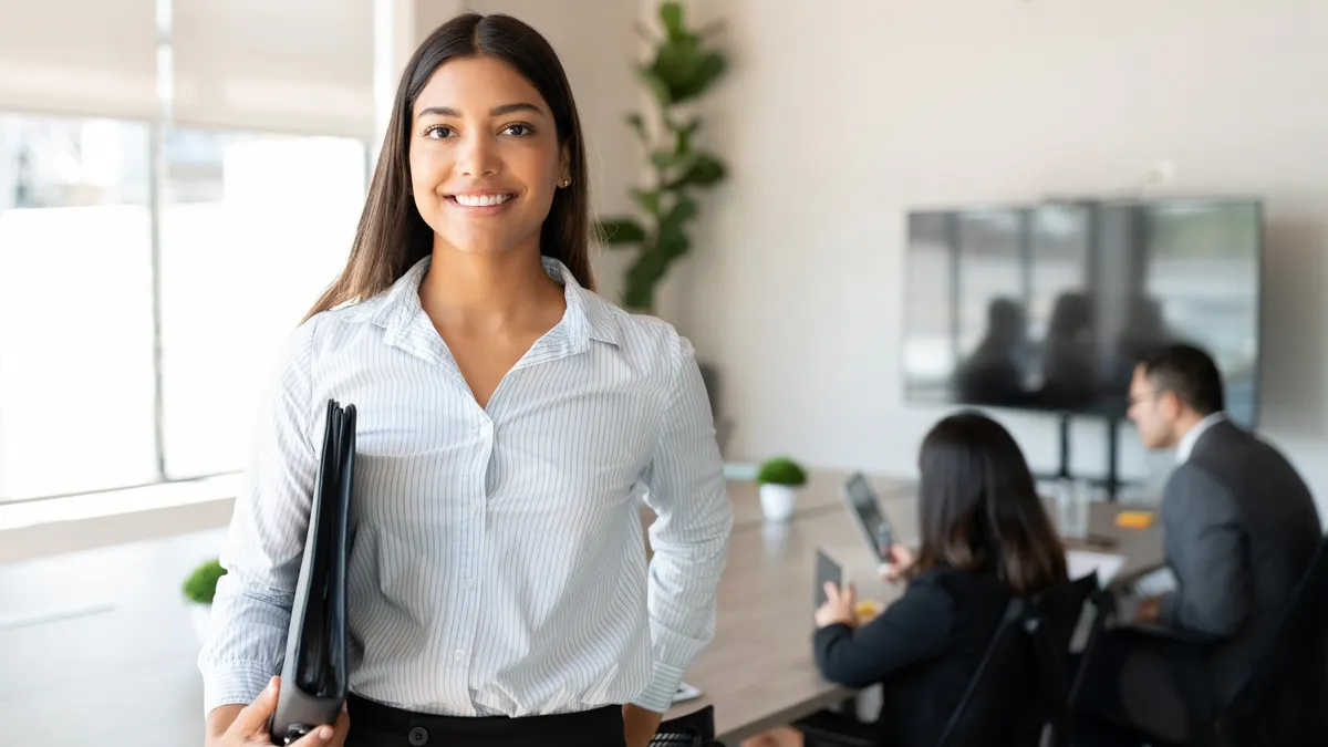 A young lawyer carries a binder out of a legal department meeting