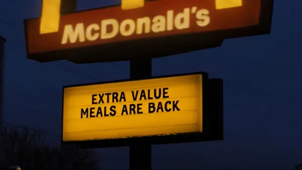 A lighted McDonald's sign at dusk reading 'Extra Value Meals are back.'