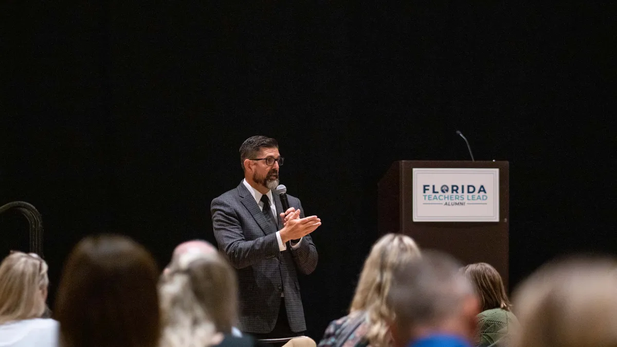 Florida Board of Education Commissioner Manny Diaz Jr. speaks to an audience holding a microphone