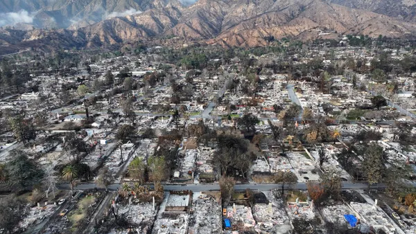 An aerial view of a burned-out neighborhood with mountains in the background.