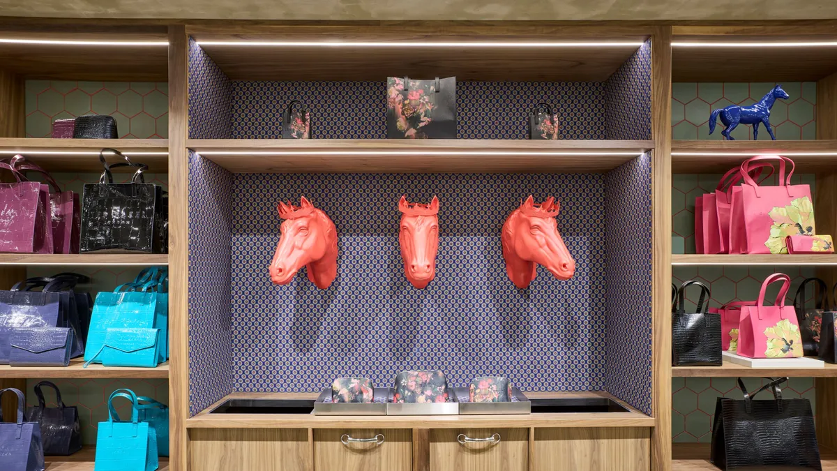 An interior wall of a store features three red horse heads alongside handbag displays.