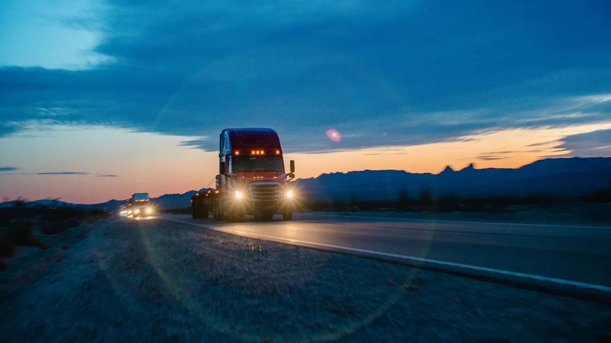 Trucks with lights on during sunset in Nevada on a dessert roadway.