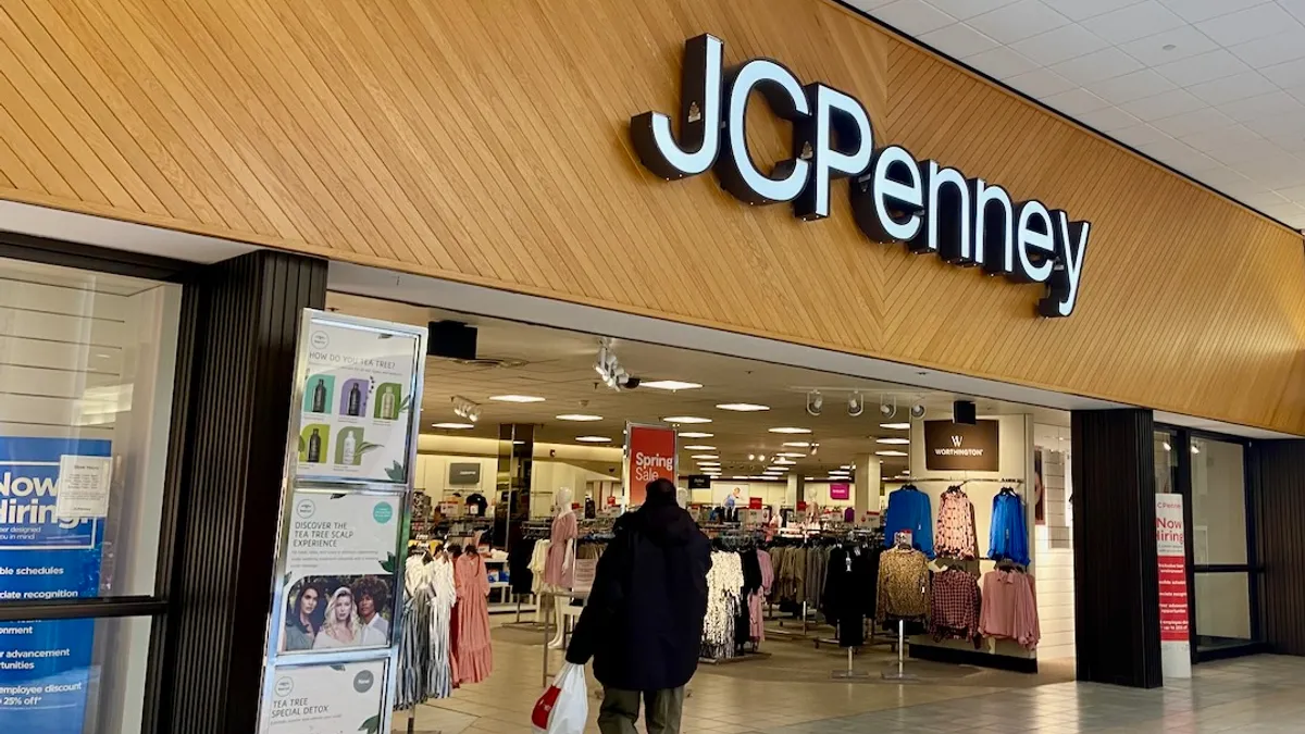 A mall store with a "JC Penney" banner in white letters on a wood-paneled background.