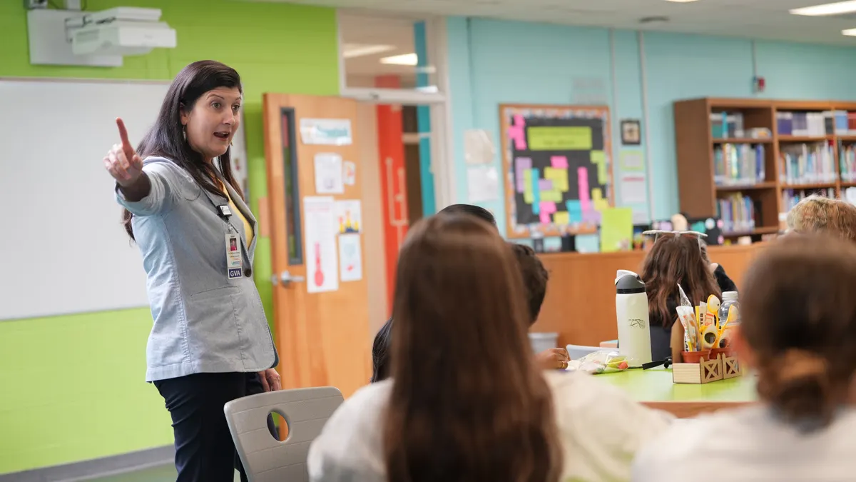 A woman educator speaks to a class of middle school students.