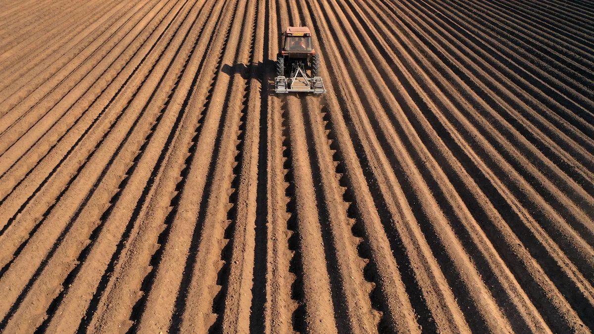 A tractor is seen in a field with defined ridges