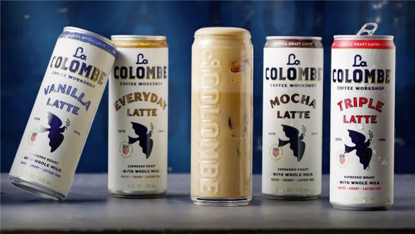 Cans of La Colombe's new ready-to-drink latte cans are lined up next to one poured in a glass over ice.