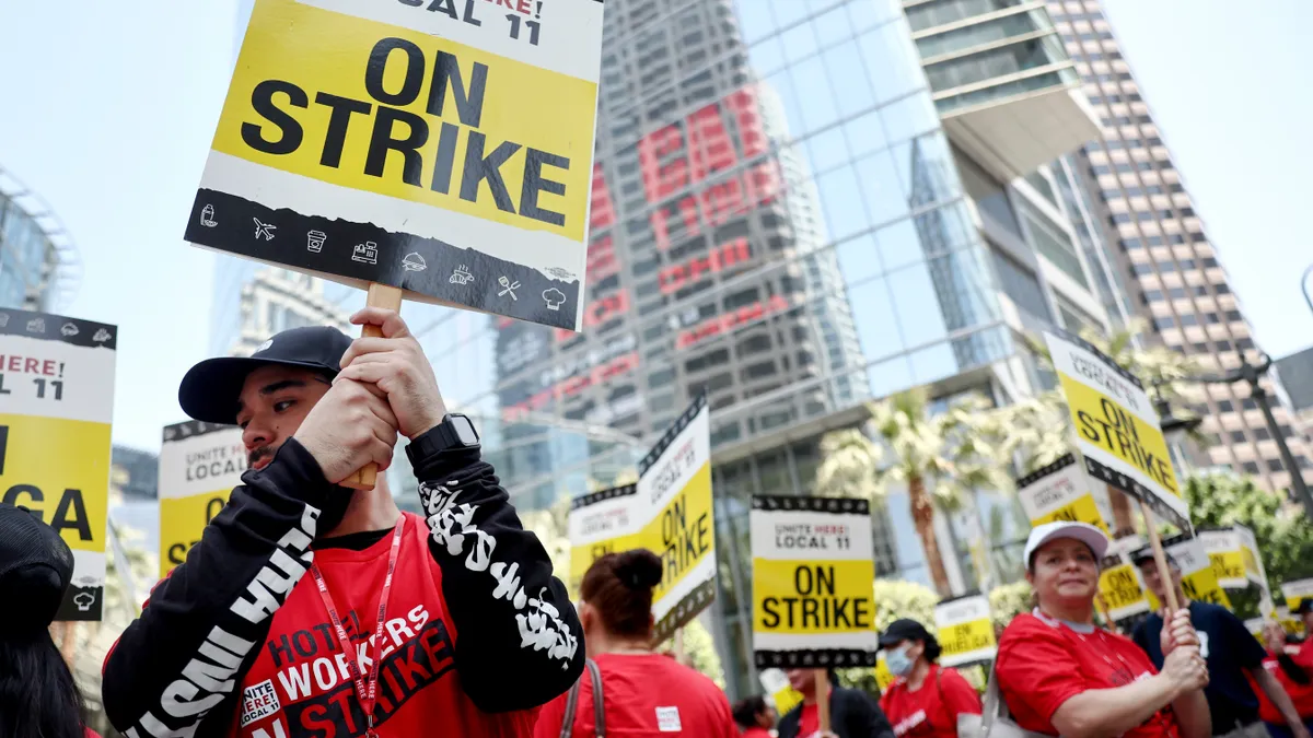 Workers in red T-shirts hold picket signs.