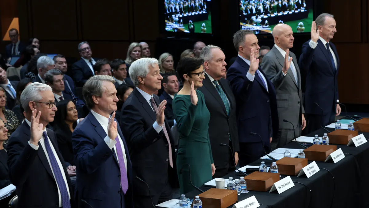 The CEOs of the eight largest U.S. banks hold up their hands as they are sworn in.