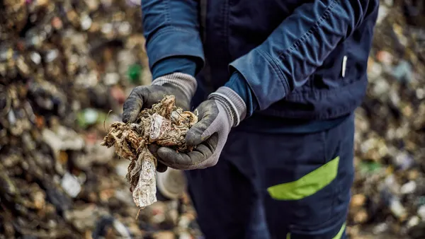 A person holds a handful of solid waste.