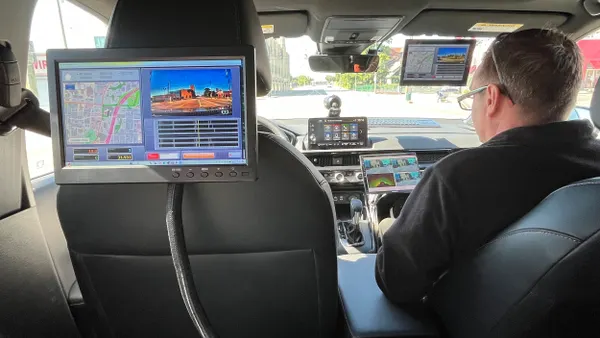 View from rear seat of a vehicle with a computer screen showing roadway map and conditions.