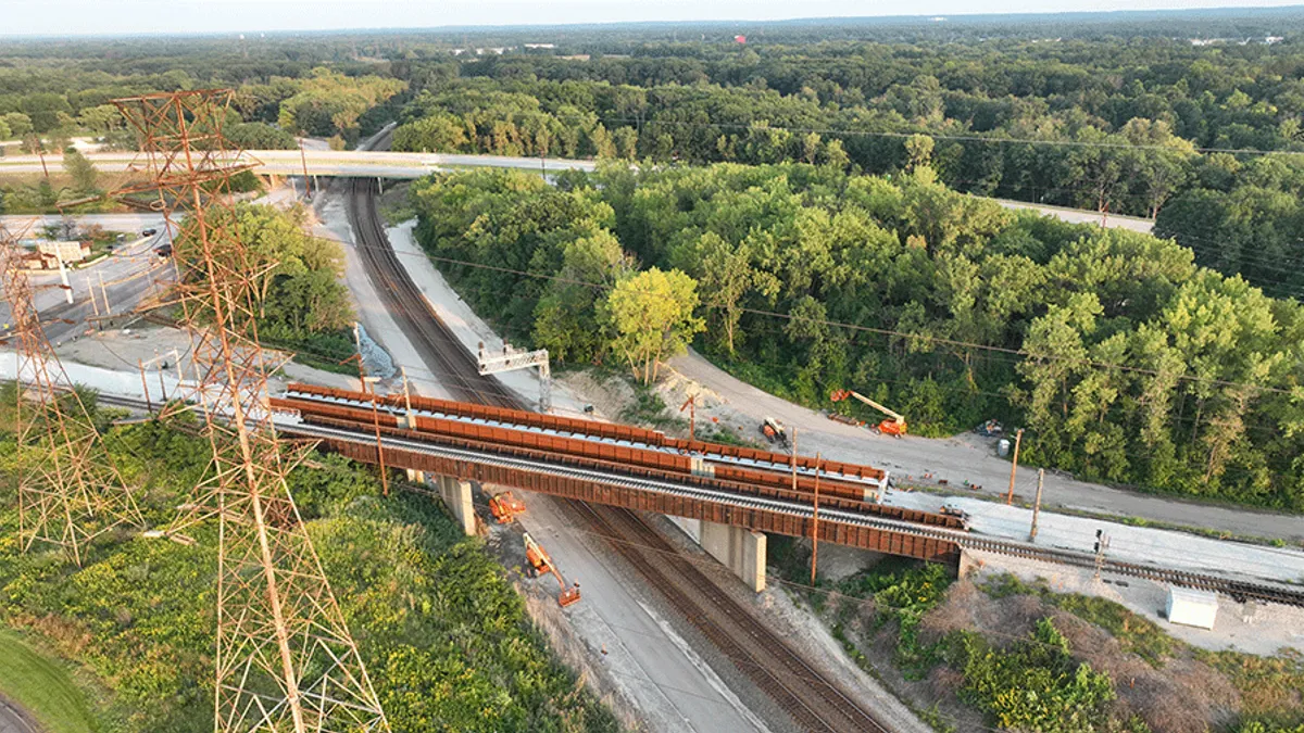 An aerial shot of train tracks passing through a wooded and plain-covered area.