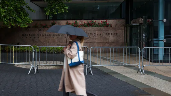 A person holds and umbrella while walking along a street outside the U.S. Court for International Trade.