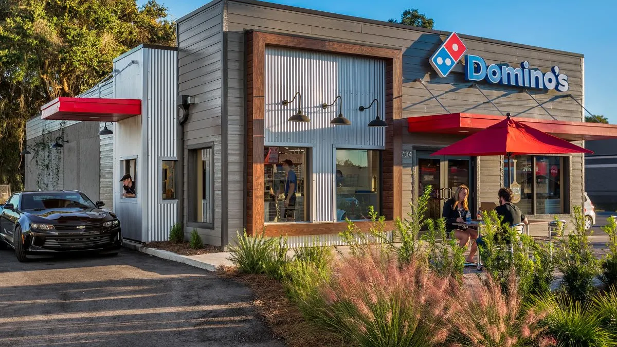 A picture of a building with Domino's signage and a car parked on the left side.